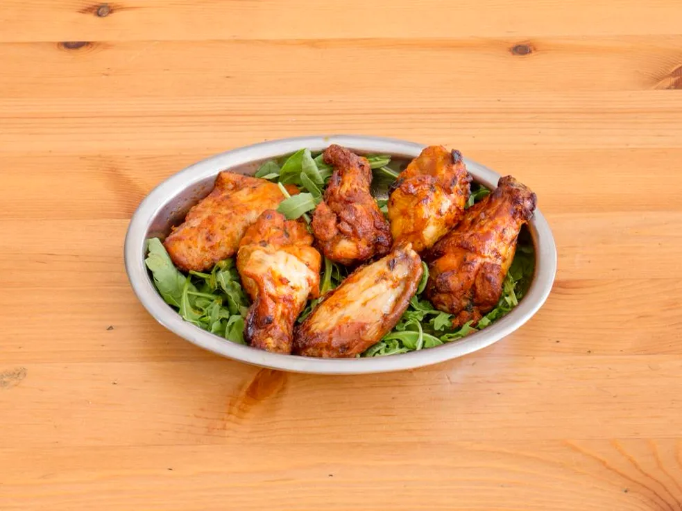 Alette di pollo piccanti su un letto di rucola