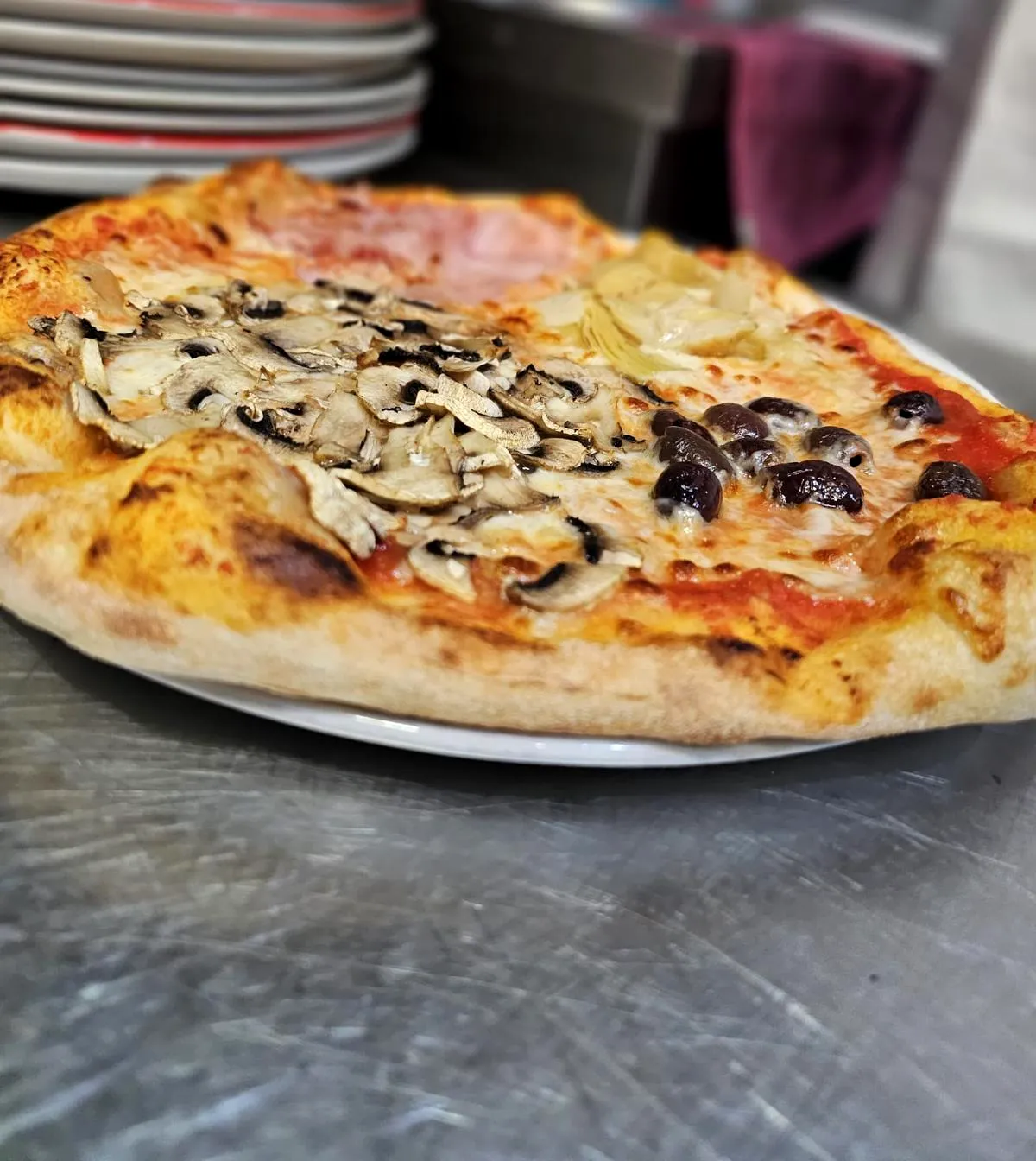 Pizza con funghi, carciofini e olive nere, appena sfornata