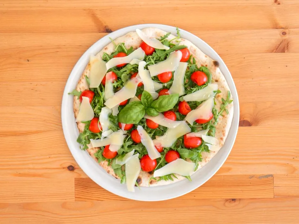 Pizza con rucola, pomodorini e scaglie di grana